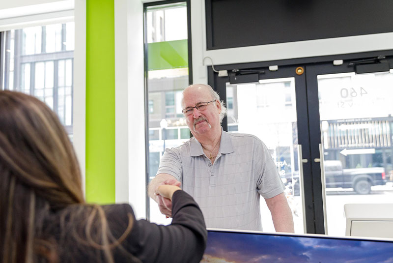 patient walking in the dental practice and greeting staff member at the front desk